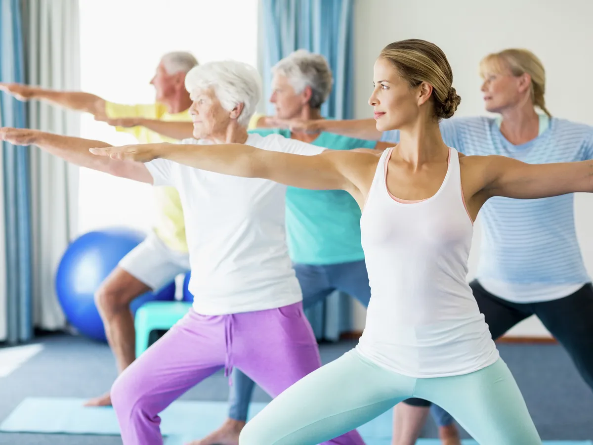A group of students of different ages holding a standing yoga pose together